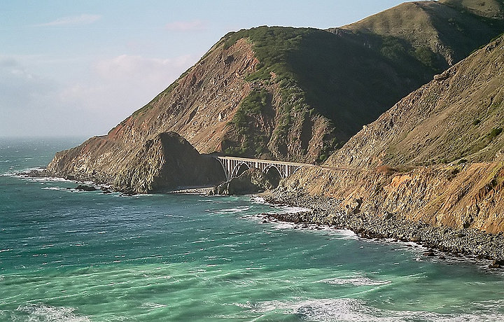 mountainous coastal road with arched bridge